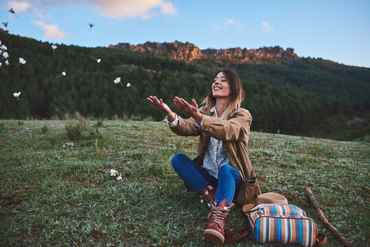 A happy woman in the mountains.She throws some flowers.