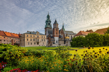 Krakow - the Royal Castle and the Cathedral Basilica of St. Stanislaus and St. Wenceslas in Wawel in the rays of the rising sun. A colorful flower garden in the foreground.