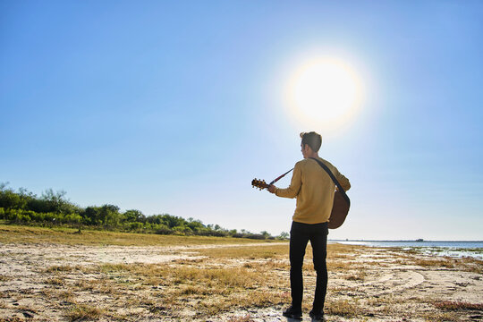 young man playing guitar in wild pl