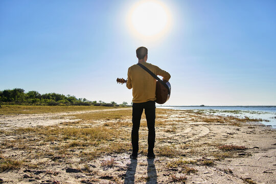 young man playing guitar in wild pl