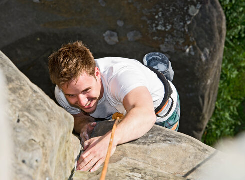 man climbing on the sandstone rocks at Harrison's Rock in England