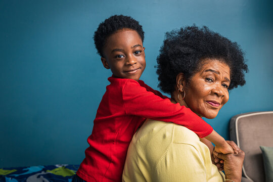 Side View Portrait Of Cute Boy With Grandmother By Blue Wall At Home