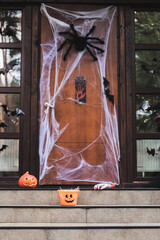 cottage entrance decorated with spider net, paper cut bats, carved pumpkin and halloween bucket