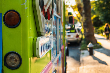 Rear left view of green ice cream truck, next to a park at sunset. 