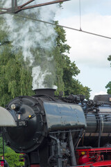 Naklejka premium Detail of a old historic steam black locomotive with smoke at station Dieren in the Netherlands