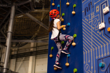 Little girl ascending in rock climbing gym
