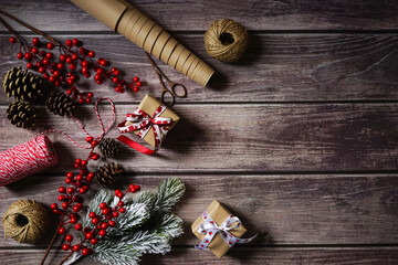 Christmas holiday background with decor, gift, berries, cones, branches on dark wooden background. Festive holiday composition. Merry Christmas. Holiday greetings. Empty space for text. Copy space.