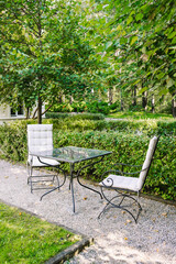 Beautiful chairs in the garden with small glass table. Nobody. Breakfast in the green park. 