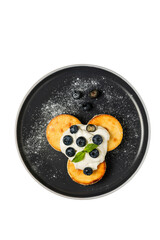 Cottage cheese pancakes with sour cream and blueberries, covered with icing sugar, a mint sprig, on a black plate. Isolated, shot from above