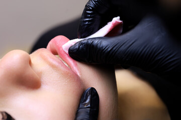 the tattoo artist is in black gloves, the guest models erase the pigment with their fingers