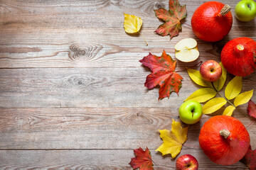 Autumn border from apples, pumpkin and fallen leaves on old wooden table.