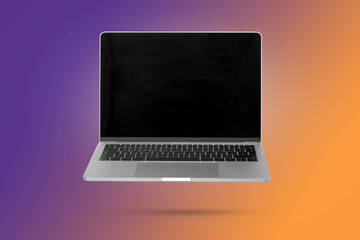 Laptop computer with empty screen while levitating in the air on a background illuminated by a purple and orange color gradient.