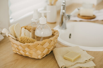 Kitchen interior with natural eco-friendly zero waste cleaning items: brushes, rugs, soap, spray and sponges in a wicker basket.