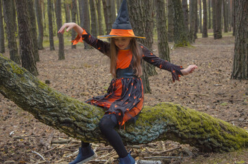 Naklejka premium a cute girl in a witch costume with a hat and cap sits on a tree like on a broomstick. halloween party