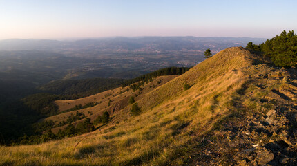 View from the top of Gostilj on the mountain Ozren on the slopes and villages in the valley, a landscape of hilly Balkans with haze on the horizon at evening
