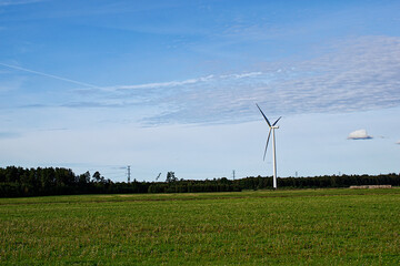 Fototapeta na wymiar Wind turbine in the middle of a field in Latvia, near Ventspils. Green electricity production concept.