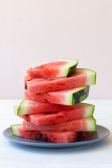 sliced watermelon on a plate.ripe red watermelon on the white background. fresh watermelon on the grey plate on the table with copy space. vertical