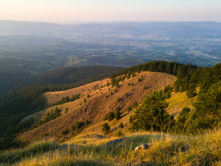 View from the top of Gostilj on the mountain Ozren on the slopes and villages in the valley, a landscape of hilly Balkans with haze on the horizon at evening