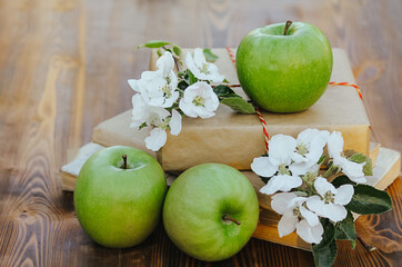 three green apples and flowers on a wooden background. harvest season