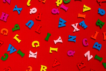 Random colorful alphabet on a red background, colorful letters.