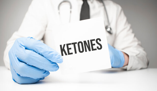 White sticker with text ketones in doctor's hands with a stethoscope