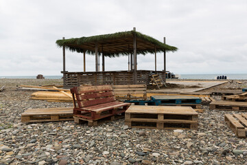 Construction of the pavilion on the beach. Pebble beach and Black Sea Batumi. Building materials, pallets.