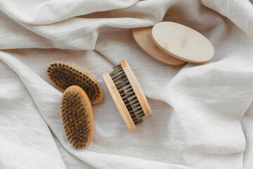 Bamboo beard brushes with natural bristles on linen textile background. Facial care concept for...