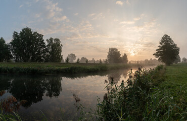 Sonnenaufgang im Spreewald, Nebel über Fluss und bewölkter Himmel