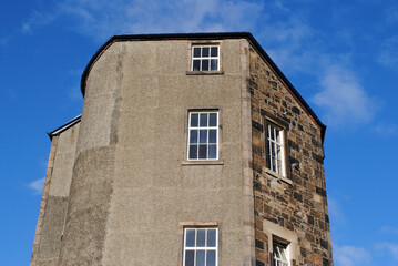 Fototapeta na wymiar Old Stone Residential Building Seen from Below against Blue Sky 