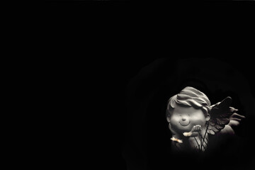 Smiling angel lying in the grass isolated on black background with copy space