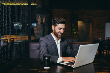 Successful businessman working on laptop during lunch break sitting in hotel restaurant