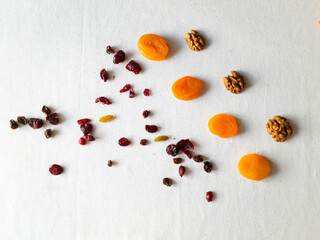 Walnuts, raisins, dried cranberries and dried apricots on white table