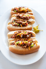 Close up of a plate of chili dogs on a white marble counter.