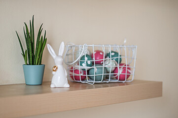 Ceramic Easter Bunny with a golden egg in his arm and eggs in basket.