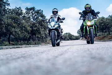 Naklejka premium biker couple riding along a mountain road with their sport bikes