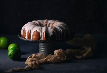 lemon bundt cake on black background accompanied by lemons