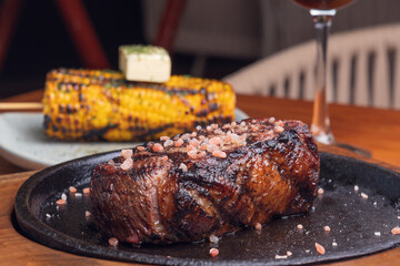 Grilled steak and garnish yellow corn on wooden table. Gourmet food.