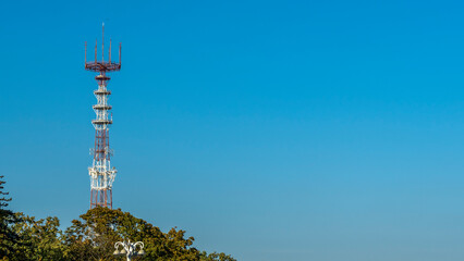 the TV and radio tower with antennas of cellular communication on the blue sky background. Space for text.