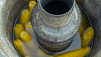 Yellow corn cooked in a tradition russian samovar. Life hack. A conceptual approach to cooking street food.
