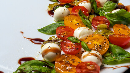 Caprese salad. Healthy meal with cherry tomatoes, mozzarella balls, spices, fresh rocket and basil.