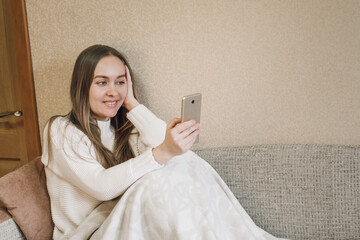 woman uses technology on his mobile phone on the sofa