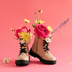 Creative layout with children's boots  with various spring flowers on a pastel pink background....