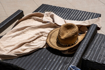Straw hat and beach towel on sunbed background