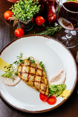 grilled turkey fillet in a plate with vegetables, herbs and sauc