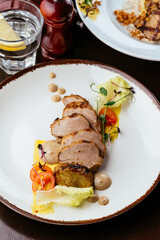 grilled turkey fillet in a plate with vegetables, herbs and sauc