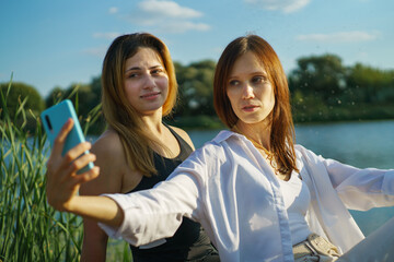 Cheerful happy women friend in nature take selfie by cellphone