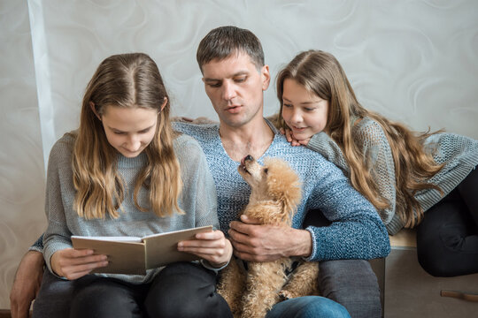 Dad with two girls and sabaka are reading a book