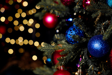 Obraz na płótnie Canvas Christmas toy ball on the Christmas tree surrounded by festive lights.