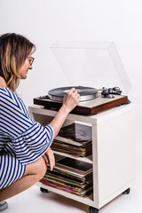 Woman dressed in blue and white striped dress putting music on a vinyl