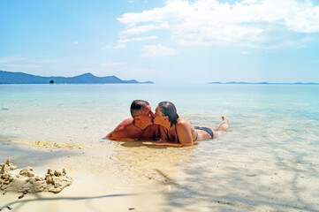 A man and a woman kiss on the beach